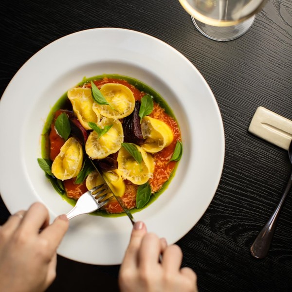 Cappeletti recheado de stracciatella ao molho de tomate, com folhas de manjericão.