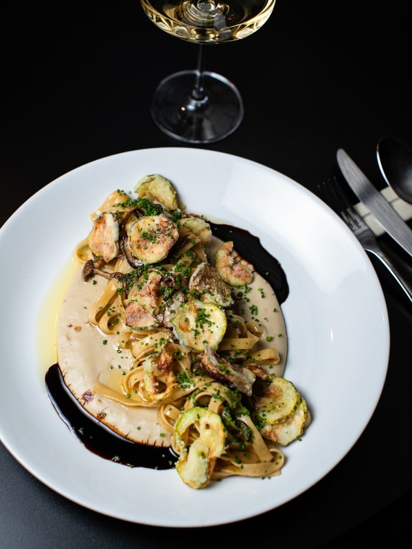 Tagliatelle ao gorgonzola com abobrinha frita, visto de cima sobre mesa escura.